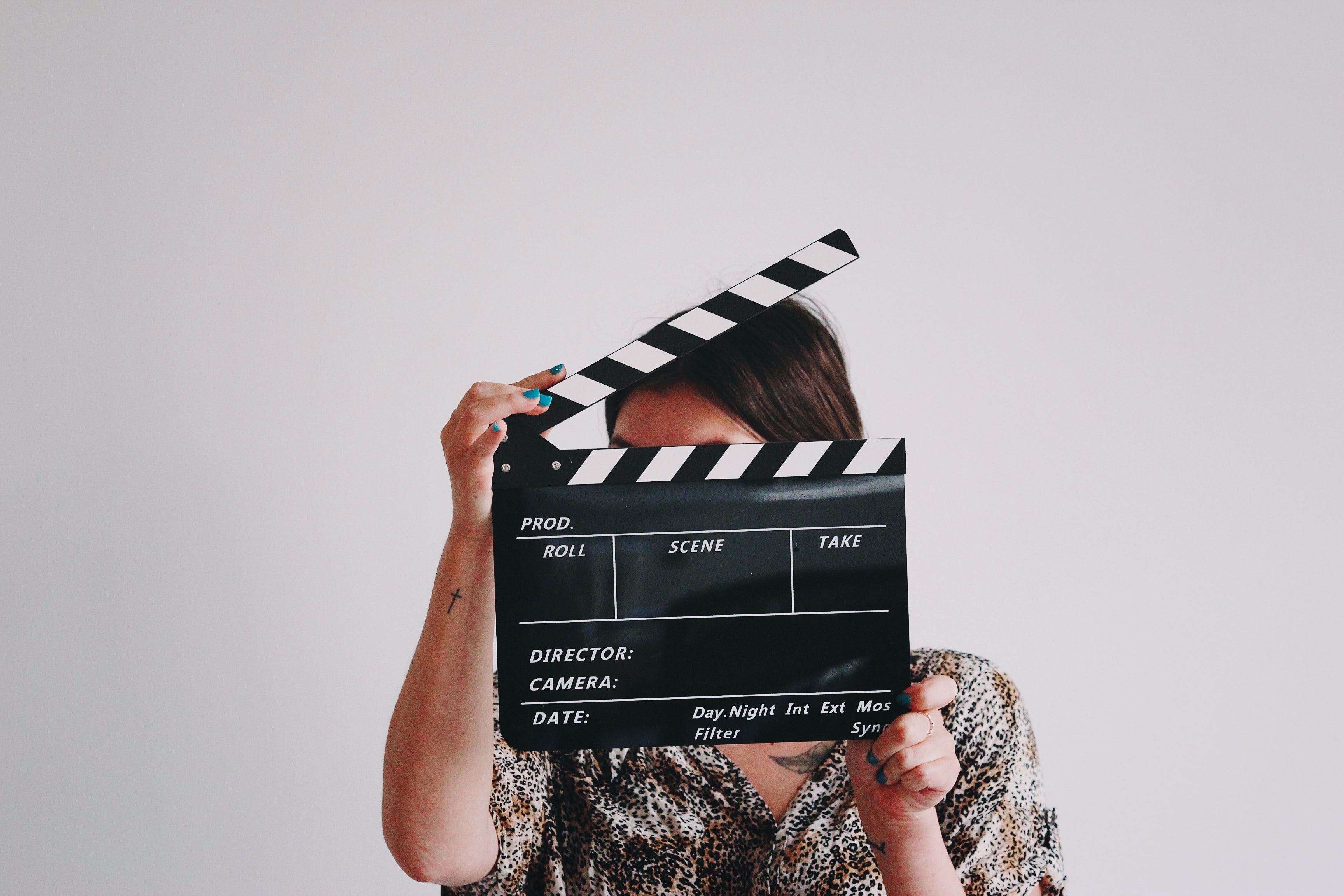 A woman holds a directing clapperboard in front of her face.